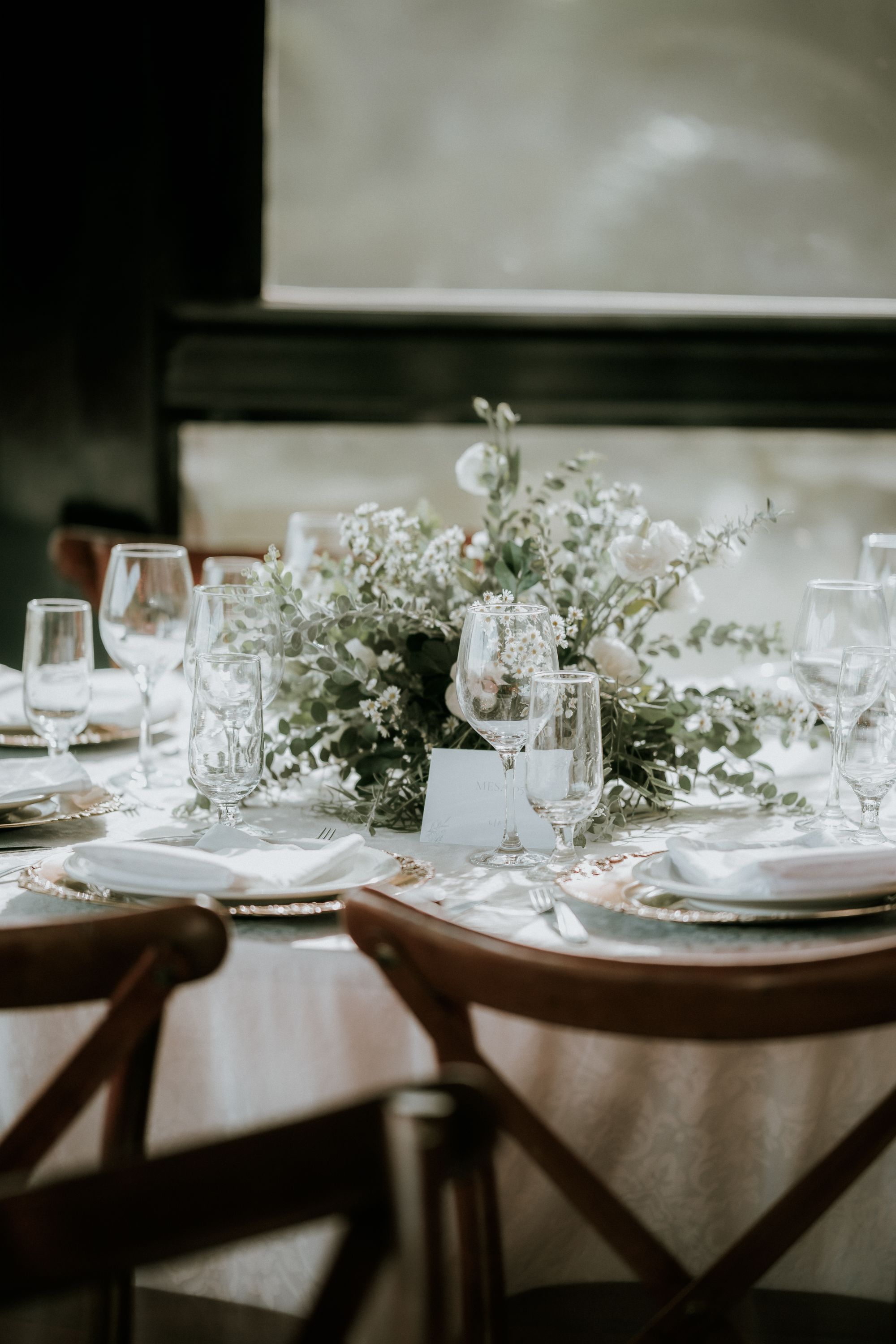 An elegant table set with white flowers, crystal glassware, and gold-rimmed place settings